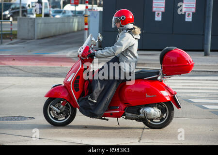 Girl on a red Vespa scooter with matching helmet on the streets of Vienna, Austria. Stock Photo