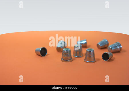 Image to write text (copy-space) next to a pile of disordered thimbles on an orange table Stock Photo