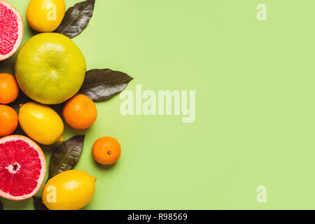 Grapefruits and lemons with leaves on a green background. Rich harvest concept. Stock Photo