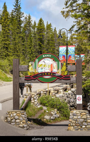 BANFF, ALBERTA, CANADA - JUNE 2018: Wooden sign post at the etnrance to the Banff Hot Springs where thermal spring water rises to the surface through  Stock Photo