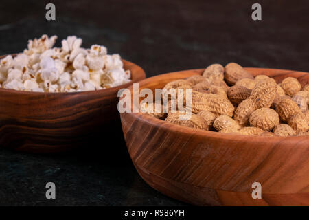 Peanuts with Popcorn in golden wood bowl on black marble table Stock Photo