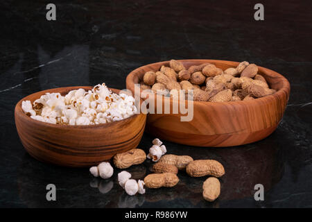 Peanuts with Popcorn in golden wood bowl on black marble table Stock Photo