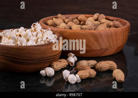 Peanuts with Popcorn in golden wood bowl on black marble table Stock Photo