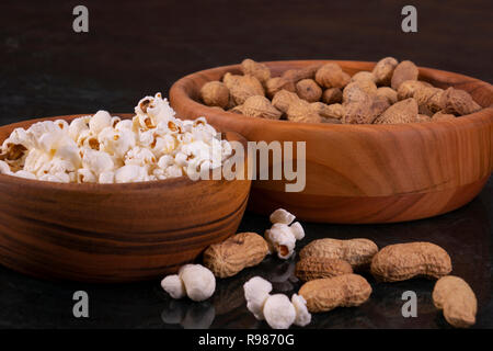 Peanuts with Popcorn in golden wood bowl on black marble table Stock Photo