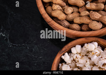 Peanuts with Popcorn in golden wood bowl on black marble table Stock Photo