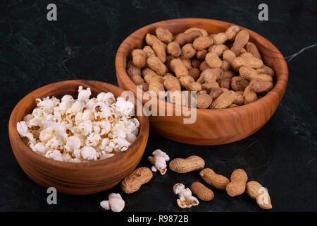 Peanuts with Popcorn in golden wood bowl on black marble table Stock Photo