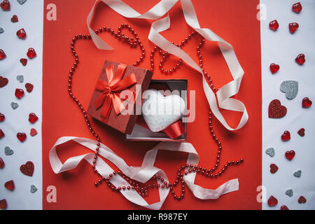 Red box and heart inside on red background. Concept for Valentine's Day or Women's Day. Stock Photo