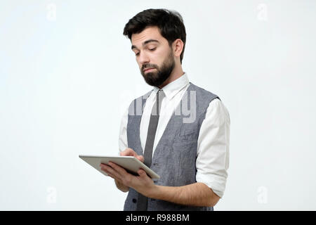 Pensive young handsome man using his digital tablet surfing in internet Stock Photo