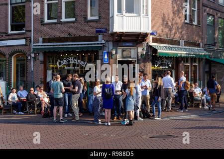 Young people drinking outside Café Heuvel in Amsterdam, Netherlands Stock Photo