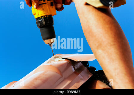 Man Using Drill To Repair Metal Roof Stock Photo