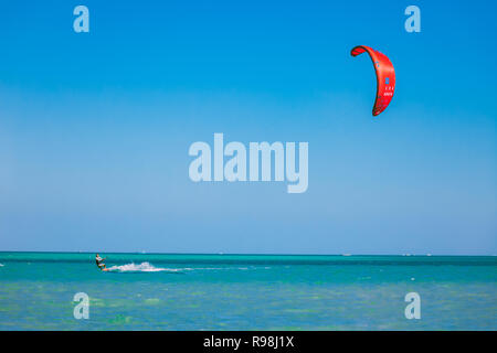 Egypt, Hurghada - 30 November, 2017: The kitesurfer with red kite gliding over the Red sea surface. Overwhelming marine scenery. The lone kiteboarder  Stock Photo