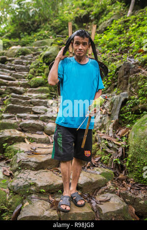 Meghalaya, India - May 15, 2017: Khasi man with a parrot pet carrying traditional bamboo basket in Meghalaya state, India Stock Photo