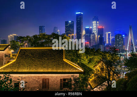CHONGQING, CHINA - SEPTEMBER 22: Night view of traditional Chinese architecture at Longmenhao old street with the modern city skyline in the backgroun Stock Photo