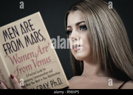 Portrait of a woman reading Men are From Mars, Women are from Venus Stock Photo