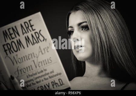 Portrait of a woman reading Men are From Mars, Women are from Venus Stock Photo