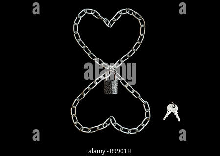 Two chained hearts locked with a padlock with keys on black background. Wedlock concept, lined with chain Stock Photo
