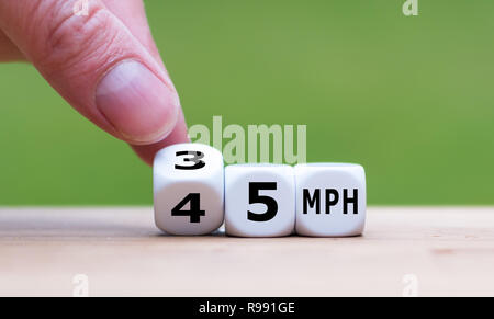 Hand is turning a dice and changes the expression '50 MPH' to '30 MPH' as symbol to reduce the speed limit from 50 to 30 miles per hour Stock Photo