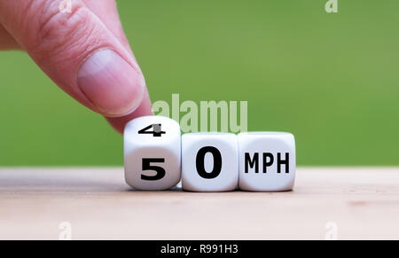 Hand is turning a dice and changes the expression '50 MPH' to '30 MPH' as symbol to reduce the speed limit from 50 to 30 miles per hour Stock Photo