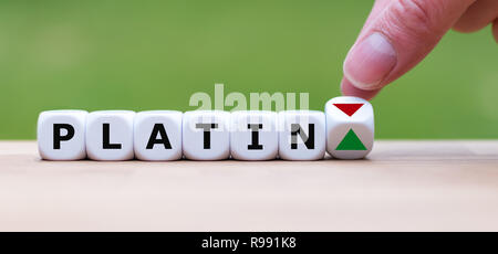 Hand is turning a dice and changes the direction of an arrow symbolizing that the price for platinum ('Platin' in german) is changing the trend and go Stock Photo