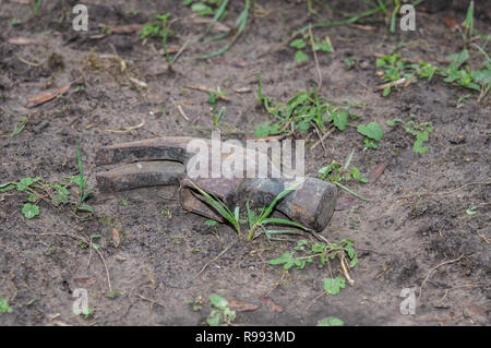 The old rusty head of a hammer abandoned in the dirt. Bokeh effect. Stock Photo