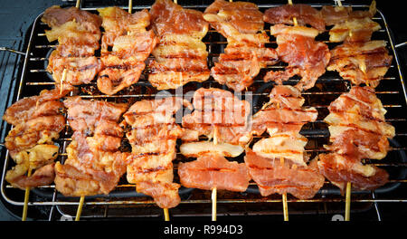 Delicious Grilled pork bamboo sticks on grille / Thai street food Barbecue toast pork Stock Photo