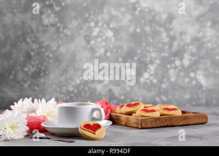 A cup of hot drink and cookies with hearts on a gray background. Beautiful still life, the mood of Valentine's Day. Side view. Stock Photo