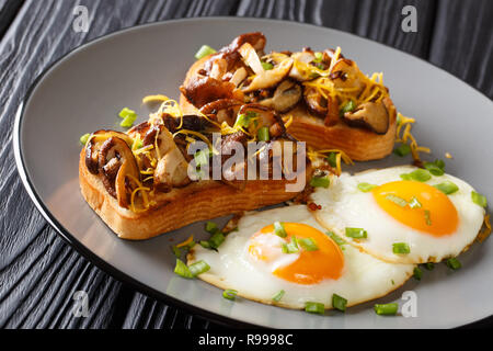 Delicious toast with shiitake mushrooms and cheddar cheese served with fried eggs close-up on a plate on the table. horizontal Stock Photo