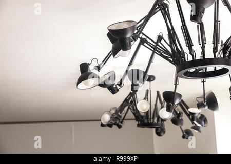 Desktop lamps made in to chandelier hanging from white ceiling Stock Photo