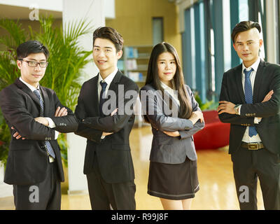 portrait of a group of young asian business people standing in office arms crossed, looking at camera smiling. Stock Photo