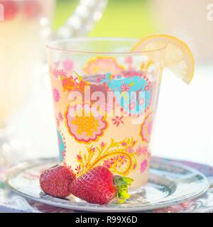 A colorful glass of lemonade with fresh strawberries as a garnish. Stock Photo