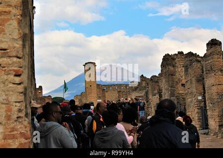 Pompeii, Italy - October 23rd 2018: Tourists survey and explore one of the many streets within the ruins of the ancient city of Pompeii. Stock Photo