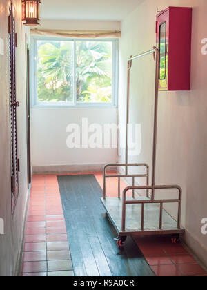 Empty hotel luggage cart on walkway in front of the door room in low cost hotel vertical style. Stock Photo