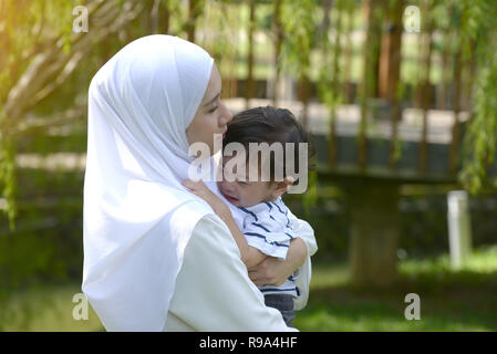 malay mother with crying son in the park Stock Photo