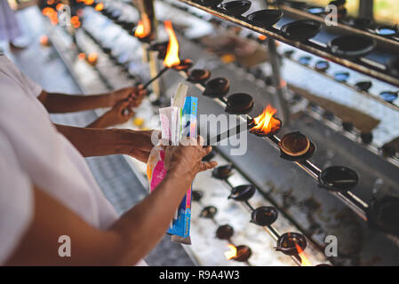 Women light incense in Ruwanwelisaya, a stupa in Anuradhapura, Sri Lanka, considered a marvel for its architectural qualities and sacred to many Buddh Stock Photo