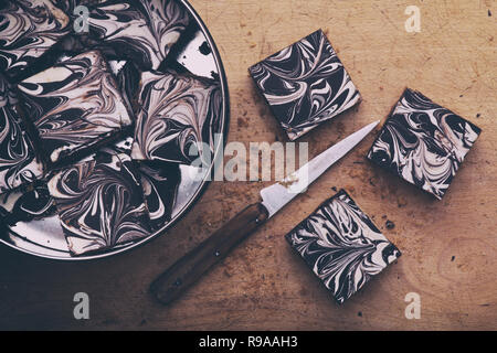Caramel shortbread / Millionaires shortbread squares in a tin with a knife on a wooden board. Vintage filter applied Stock Photo