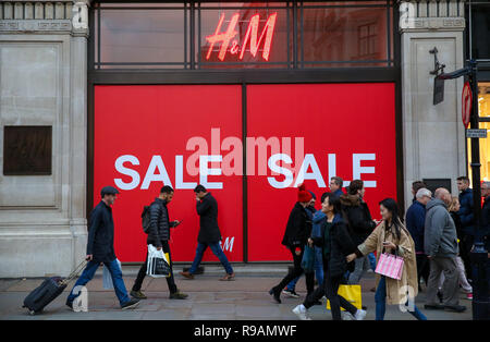 Shoppers are seen walking past H&M window display with a large SALE sign.  Last minute Christmas shoppers take advantage of pre-Christmas bargains at  Oxford Street in London. Fewer shoppers have been reported