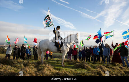 Lockerbie, Scotland, UK. 22nd December, 2018. A Walk for Peace up Burnswark near Lockerbie in memory of those who died in the Lockerbie Disaster. Krystal Anderson on Rebel with the Lockerbie Standard. The walk follows the age-old tradition in Scotland of taking to the hills to find peace and contemplate the future. The walk up Burnswark with the flags of the 21 nations that the victims from the Pan Am flight 103 came from was organises by representatives from Allanton World Peace Sanctuary and local artists Credit: Allan Devlin/Alamy Live News Stock Photo