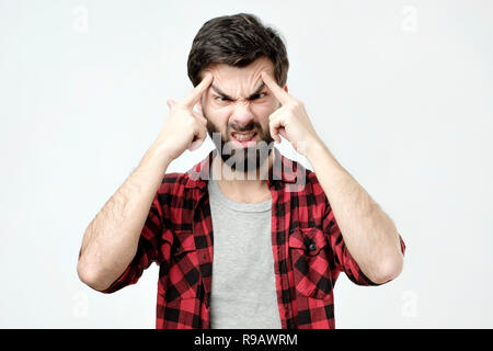 Portrait of concentrated man, lifts eyebrows with fingers. Stock Photo
