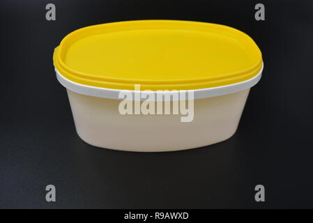 White plastic container for food and mayonnaise with a yellow cap on a black stylish background. Stock Photo