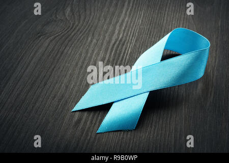 Blue awareness ribbon on a black desk. Prostate Cancer. Stock Photo