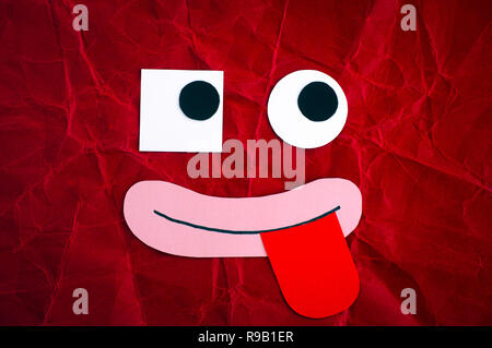 Funny face with different eyes and tongue stuck out. Emotional face made from paper. Stock Photo