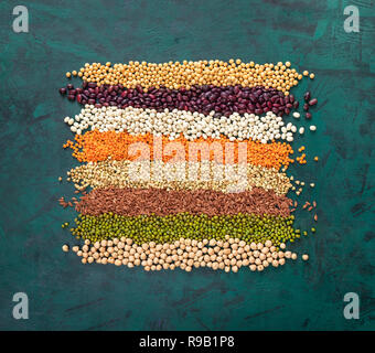 Square of superfoods laid out stripes, in middle of textured emerald green background. Top view. Flat lay.  Healthy food rich with protein. Superfoods Stock Photo