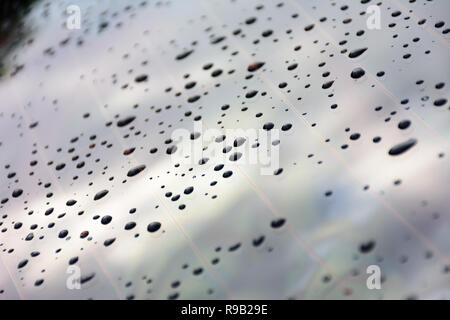 Raindrops splatter on the glass of car window. Stock Photo