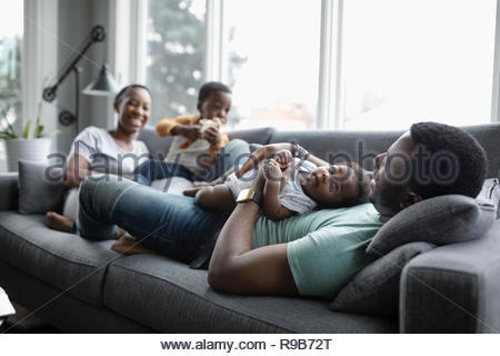 Young family relaxing on living room sofa