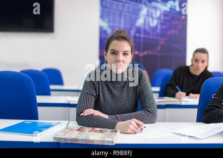 young beautiful female student writing notes in the classroom Stock Photo