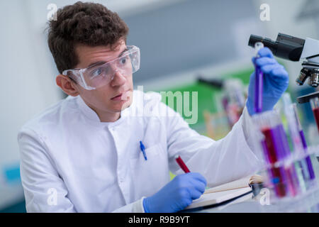 young student with protective glasses making chemistry experiment in bright laboratory,education and medicine concept Stock Photo