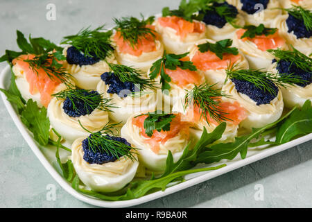 Stuffed eggs with salmon and caviar decorated by parsley and dill. Party food Stock Photo