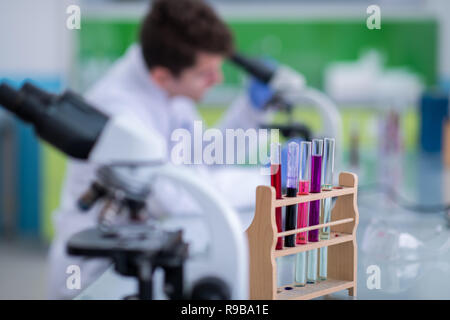 Young student scientist looking through a microscope while doing some research in the laboratory Stock Photo