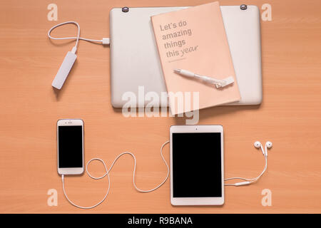 Business new technology, on the desk: laptop, power bank, mobile phone, tablet, headphones, new year notebook and pen with memory stick inside Stock Photo