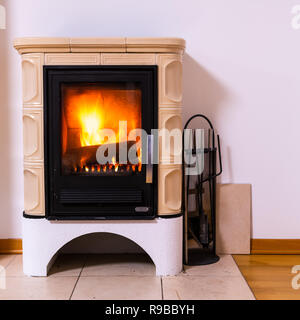 Tiled stove with fire burning inside, cosy and warm interior scene, heating in winter Stock Photo